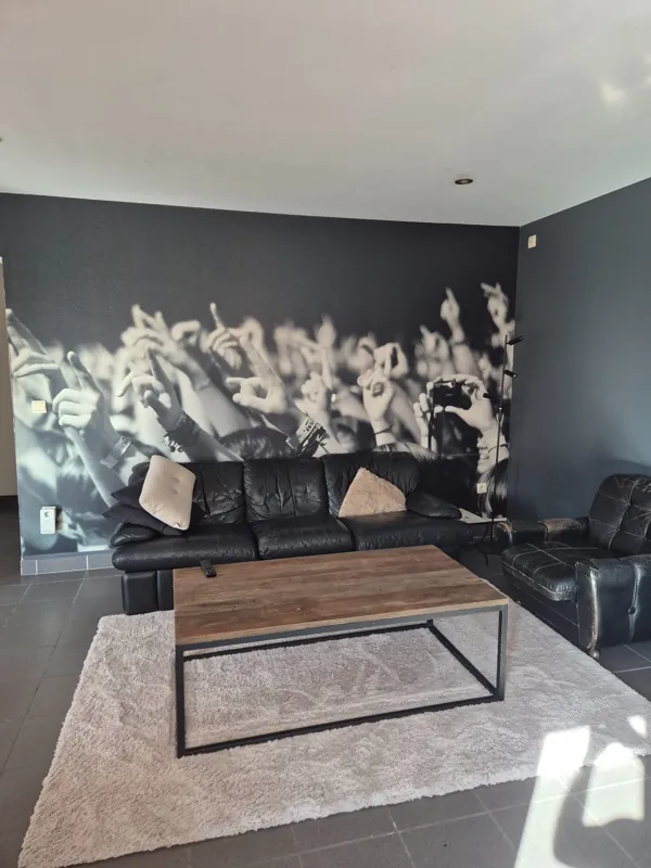 Het salon met een bank, fauteuil, koffietafel en een grote fotowand